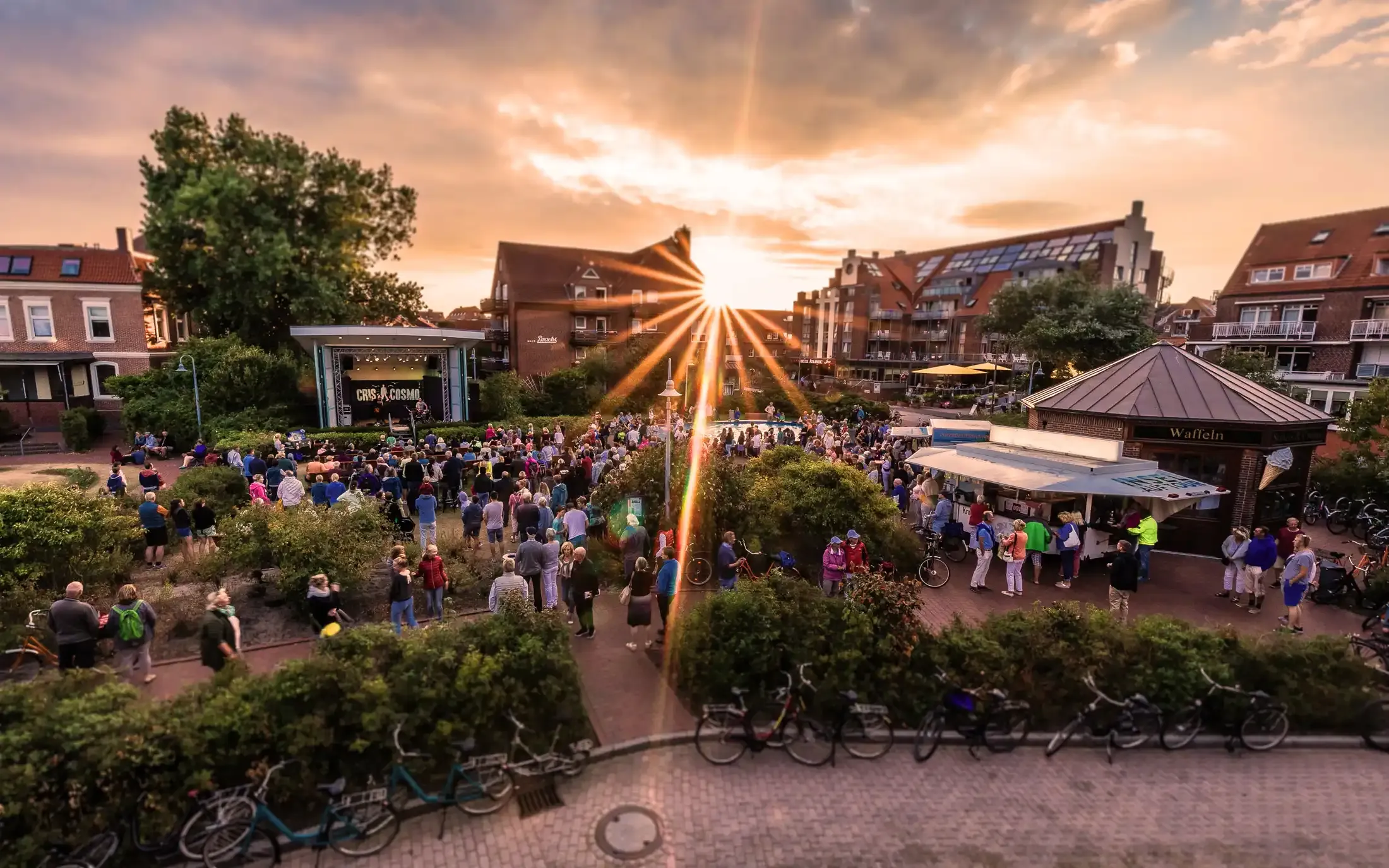 Blick von oben auf den Kurplatz Juist mit Bühne, Ständen und Publikum im Sonnenuntergang